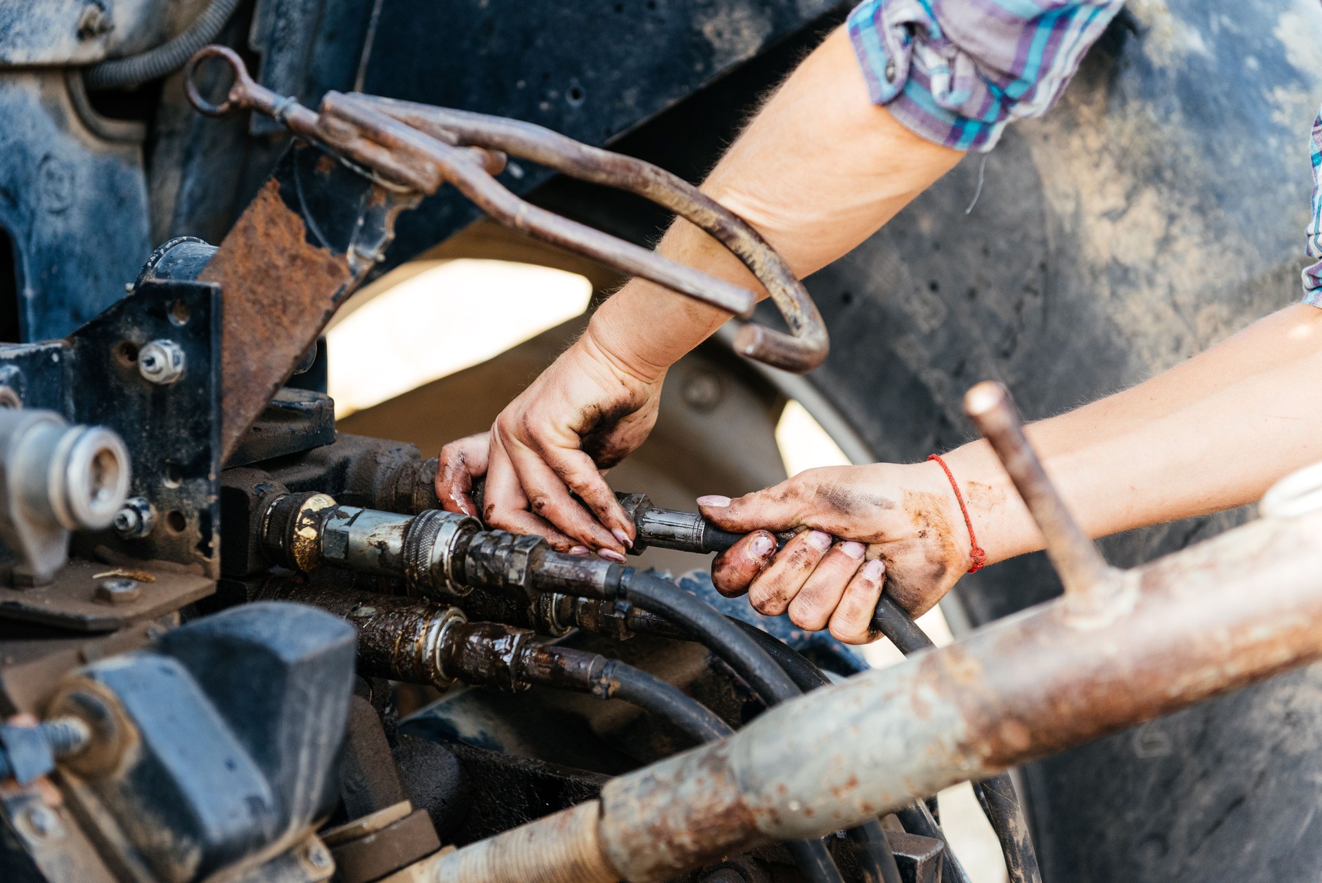 Crop mechanic repairing tractor at farm during day