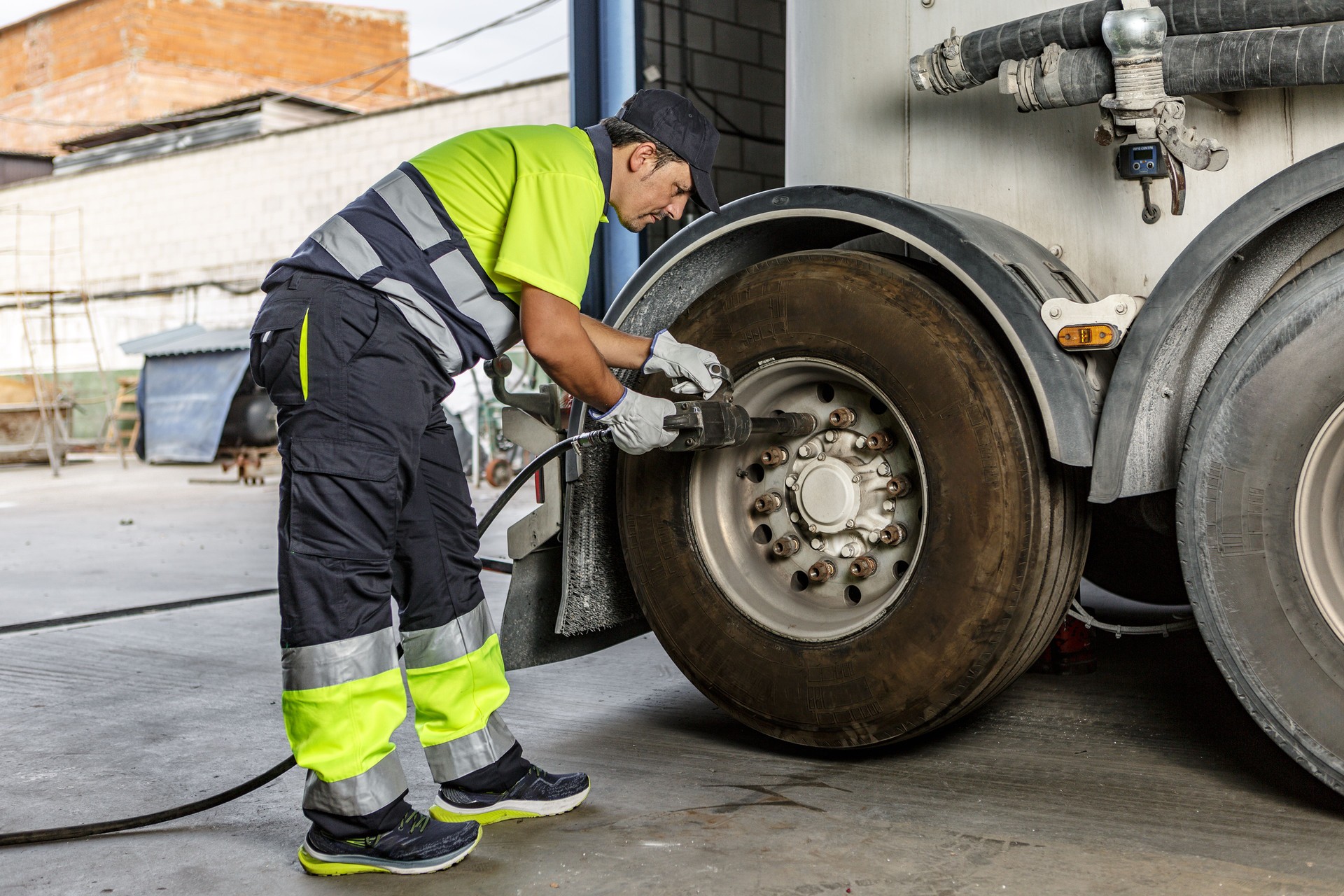 Mechanic tightening wheel of truck in workshop