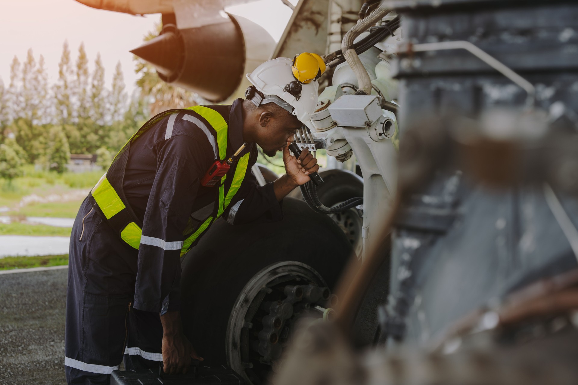 Mechanics inspect the engines of a large plane before takeoff at a summer airport.